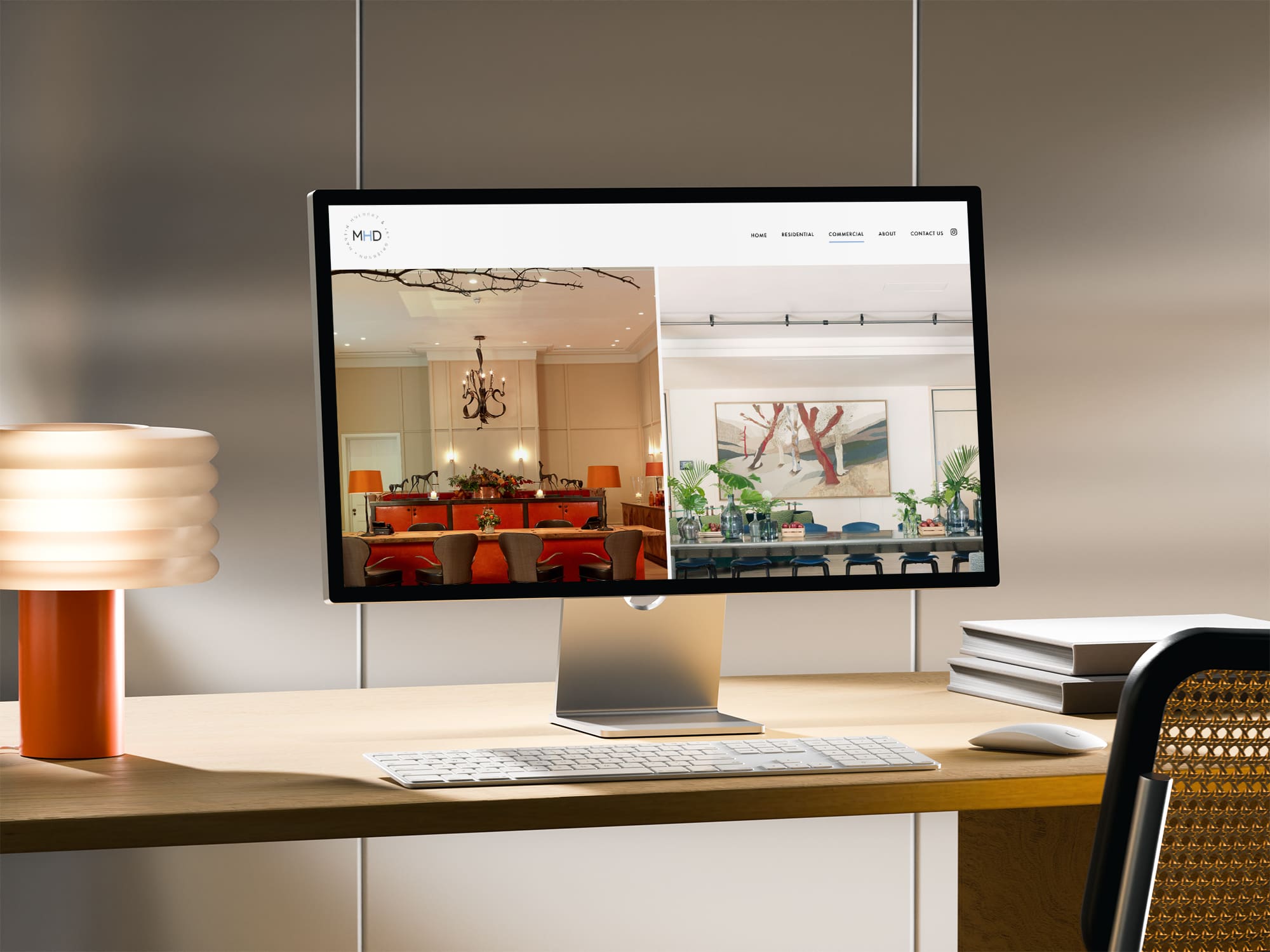 A desktop computer on a wooden desk displays a website featuring interior images of modern dining spaces; a lamp, keyboard, and chair are also visible.